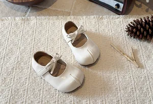 Detail view of cream white girls' Mary Jane shoes featuring a bow and soft sole