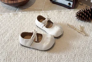 Elegant white Mary Jane shoes for girls featuring a cute bow and soft sole detail.