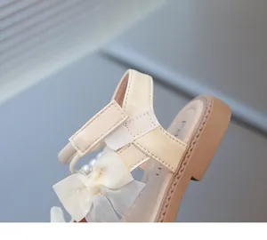 Close-up detail of girls' princess sandals featuring a delicate mesh bow and pearl accents.