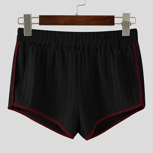 Close-up detail of men's ribbed casual shorts with contrast red piping on a wooden hanger