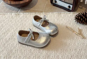 Close-up of silver girls' Mary Jane shoes with elegant bow detail and soft sole