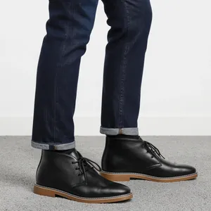 Zijaanzicht detail van zwarte leren chukka boots voor heren met bruine zool
