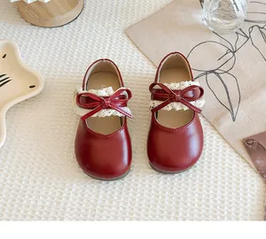 Draufsicht auf rote Mädchenschuhe aus Leder mit zarter Spitze und Schleifendekoration.