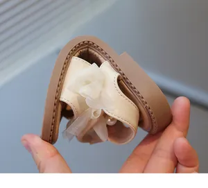 Detailed view of flexible soft sole on beige girls' princess bow sandals for kids