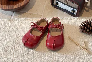 Detailed view of red girl's Mary Jane split-toe shoes with bow tie in retro setting