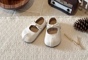 Detail view of white Mary Jane shoes for girls featuring a bow and split-toe design