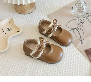 Detailansicht brauner Mädchen-Mary-Janes aus Leder mit Spitze und Schleifenverzierung.