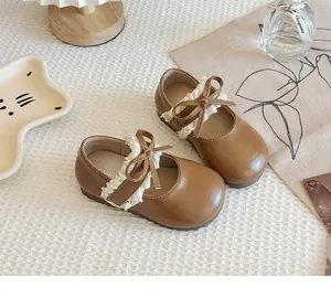 Nahaufnahme brauner Mädchen-Lederschuhe mit zarter weißer Spitze und schöner Schleife