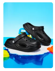 Detailweergave van zwarte antislip kinderklompen in een strandscène met speelgoed