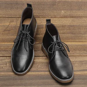 Bovenaanzicht van zwarte lederen desert boots voor heren op een rustieke houten vloer