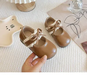 Nahaufnahme brauner Lauflernschuhe für Mädchen mit zartem Spitzenbesatz und Schleife