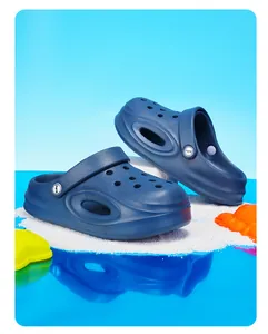 Marineblauwe kinderklompen met ademende gaten en antislipzool op het witte strand.