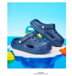 Gedetailleerde foto van marineblauwe kinderklompen op wit zand met kleurrijk zomers strandpakket