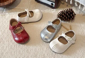 Close-up of girls' Mary Jane shoes in red, white and silver with bow detail