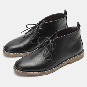 Detailopname van zwarte heren desert boots met lichtbruine zolen en witte stiksels