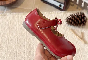 Close-up detail of a glossy red Mary Jane shoe for girls featuring a cute bow and soft sole.