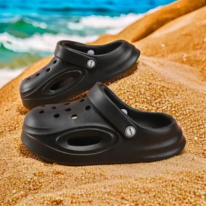 Ademende zwarte kinderklompen met antislipzolen op een schilderachtige zandstrand achtergrond