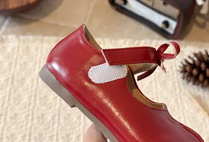 Close-up view of red girls' Mary Jane shoes with bow detail and easy hook-and-loop closure