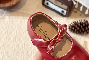 Close-up detail of red girl's Mary Jane shoe with bow accent and British style design