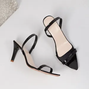Close-up of black patent leather pointed-toe stiletto sandals with single strap