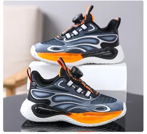 Close-up detail of boys' athletic sneakers featuring an orange rotary buckle lacing system