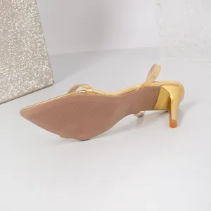 Close-up detail showing the sole and slim stiletto heel of an elegant gold pointed-toe sandal.