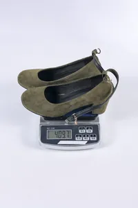 Olijfgroene suède pumps met blokhak gewogen op een digitale weegschaal, 409,7 g.