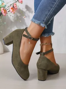 Close-up van olijfgroene suède pumps met stevige blokhakken en gekruiste enkelbandjes