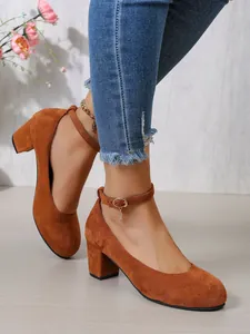 Detailopname van bruine suède pumps met blokhak en elegante enkelbandjes