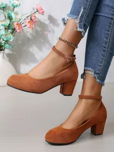 Detailopname van elegante bruine suède pumps met stevige blokhak en enkelbandje