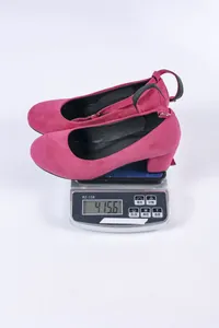 Detailoverzicht van roze suède pumps met blokhak gewogen op 415,6g op een digitale weegschaal.