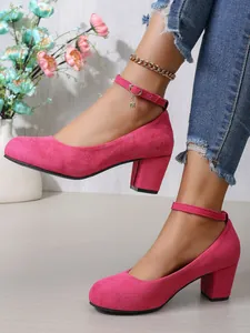 Macro-opname van fuchsia suède pumps met blokhak en een elegant detail aan het enkelbandje.