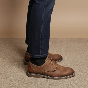 Vue latérale de chaussures en cuir marron vintage pour hommes portées avec un jean