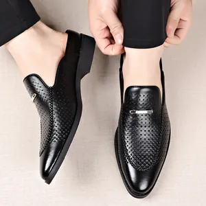 Zuecos de cuero negro perforado para hombre con detalle metálico y diseño fácil de calzar.
