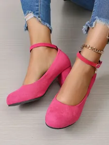 Detailopname van stijlvolle fuchsia suède Mary Jane-pumps met blokhak en enkelband.