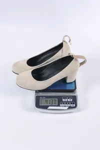 Beige suède pumps met ronde neus en blokhak, wegend 413,7g op een digitale weegschaal