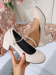 Detailweergave van beige suède Mary Jane pumps met blokhak en elegante ronde neus