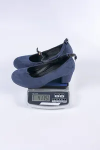 Detailweergave van het gewicht van 417,5 g van blauwe suède pumps met blokhak op een weegschaal