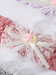Detailansicht eines Baby-Spitzenstirnbands mit Häkelarbeit und Satin-Blumenbögen