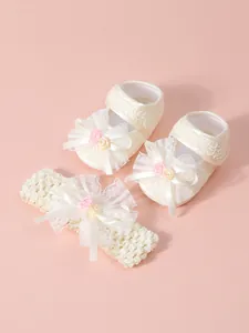 Entzückendes Set aus cremeweißen Babyschuhen aus Spitze und passendem Stirnband für Mädchen