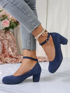 Detailweergave van marineblauwe suède pumps met blokhak en enkelbandjes