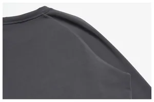 Primo piano della cucitura della manica raglan su una maglia sportiva grigio scuro da uomo.
