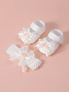 Detailansicht der weißen Spitzen-Babyschuhe und passendes Stirnband-Set für kleine Mädchen