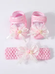 Detaillierte Nahaufnahme von rosa Baby-Spitzenschuhen und passendem Blumen-Stirnband-Set.