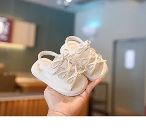 Gros plan de sandales blanches pour bébé avec nœuds décoratifs et semelles souples.