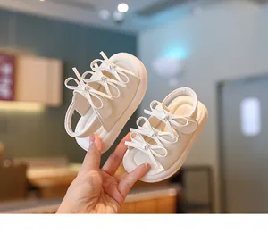 Gros plan de sandales beiges élégantes pour bébés avec de jolis nœuds et semelles souples