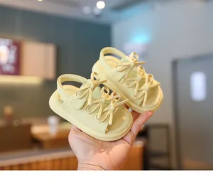 Gros plan de sandales pour bébé à semelle souple avec jolis nœuds en jaune clair.