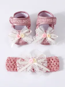 Detailansicht von rosa Spitzen-Babyschuhen und passendem Stirnband-Set mit Blumen