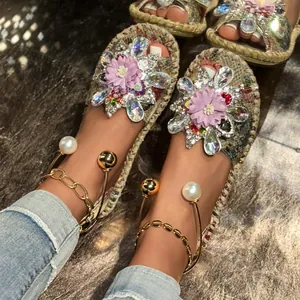 Detailed close-up of bohemian flat sandals with purple flowers, pearls, and crystals.