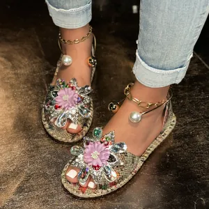 Close-up of decorative flat sandals featuring pink flowers and colorful crystal beads